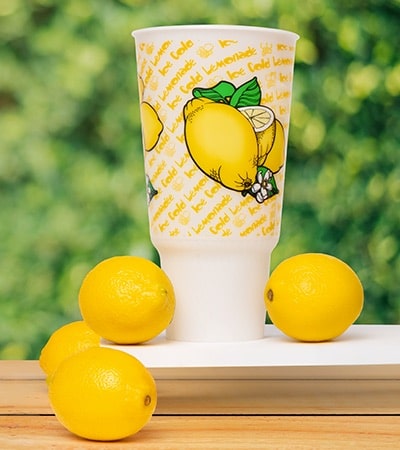 a lemonade cup with lemons around it